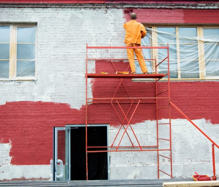 Man painting a brick wall in red